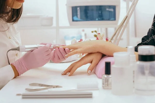 Manicure aplicando esmalte nude nas unhas de uma cliente